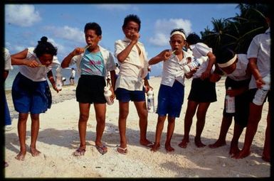 Schoolchildren brushing teeth on beach, Rakahanga, Cook Islands