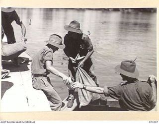 ALEXISHAFEN, NEW GUINEA. 1944-05-15. MEMBERS OF THE 2/15TH FIELD AMBULANCE UNLOAD MAIL FROM AN OLD BOAT. THE BOAT, RETRIEVED FROM THE SEA BED, IS NOW USED TO TRANSPORT MAIL AND PASSENGERS TO ..