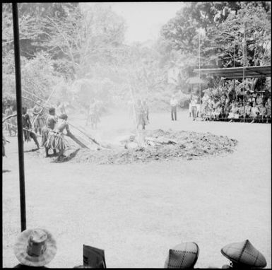 Fijian men, dressed in traditional costumes, leveling stones in the fire, Fiji, 1966 / Michael Terry