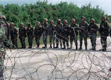 US Army (USA) Soldiers assigned to A/Company, 1ST Battalion, 17th Infantry Division armed with 5.56mm M16A2 assault rifles form a scrimmage line behind a concertina wire barrier while practicing riot control techniques at Orote Point, Guam, during Exercise TANDEM THRUST '99