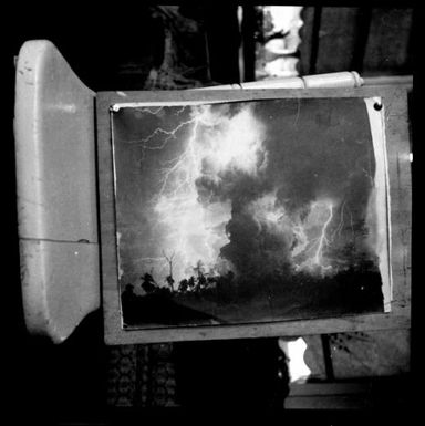 Photograph of a photograph showing an electrical storm with volcanic smoke and a road, Rabaul, New Guinea, 1937 / Sarah Chinnery