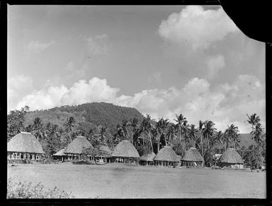 View of fale tele thatch roof native huts, with palm trees and forest covered hills beyond, Apia, Western Samoa