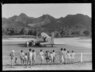 Truck loading a C47 transport aircraft, Rarotonga airfield, Cook Islands, including local children watching in the foreground