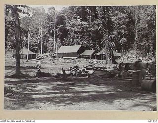 SORAKEN AREA, BOUGAINVILLE. 1945-04-03. THE QUARTERMASTER'S STORE, CANTEEN AND REGIMENTAL AID POST, 11 INFANTRY BRIGADE, AND THE AREA AROUND BUILDINGS WHICH HAS BEEN CLEARED FOR CAMP SITE