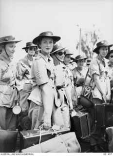 LAE, NEW GUINEA, 1945-05-07. AWAS WHO ARRIVED IN LAE FROM AUSTRALIA ON THE MV DUNTROON, NOW DISEMBARKED BY LANDING BARGES, WAIT FOR THE TRUCKS TO TRANSPORT THEM TO THE AWAS BARRACKS AT BUTIBUM ..