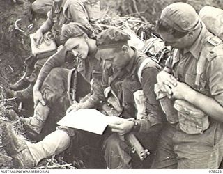 BOUGAINVILLE ISLAND. 1944-12-30. TROOPS OF THE 25TH INFANTRY BATTALION READING THE AUSTRALIAN ARMY NEWSPAPER, "GUINEA GOLD" WHILE AWAITING THE ORDER TO ADVANCE ON JAPANESE POSITIONS IN THE ..