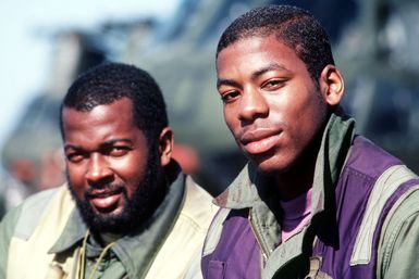 Two flight deck crewman take a break from flight operations aboard the amphibious assault ship USS GUAM (LPH 9). The ship is deployed off the coast of Lebanon