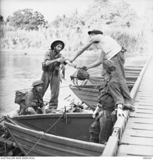 KALIKODOBU, NEW GUINEA. 1942-10. MEMBERS OF THE 2/14TH AUSTRALIAN INFANTRY BATTALION BEING HELPED ASHORE BY UNITED STATES SERVICEMEN AT THE UNITED STATES BASE CAMP WHARF. THESE SOLDIERS WERE OUT ..