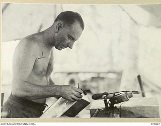 ALEXISHAFEN, NEW GUINEA. 1944-09-13. NX89584 CRAFTSMAN F.L. WHITAKER, TINSMITH, SOLDERING A METAL CONTAINER IN THE SHEETMETAL SHOP OF THE 133RD BRIGADE WORKSHOP