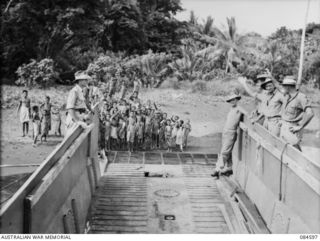 BUKAWA, HUON GULF, NEW GUINEA. 1944-12-14. 43 LANDING CRAFT COMPANY MEMBERS FAREWELLING NATIVES AS THEIR BARGE MOVES OUT TO SEA FOLLOWING A PERIOD OF EXCHANGING TINNED FOOD FOR FRUIT AND SOUVENIRS