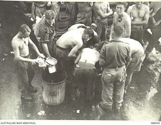 AT SEA. 1945-03-31. HEADQUARTERS 26 INFANTRY BRIGADE TROOPS ABOARD THE VAN HEUTSZ WASHING THEIR DIXIES AFTER BREAKFAST ON THE TOP DECK DURING THEIR MOVEMENT TO MILNE BAY