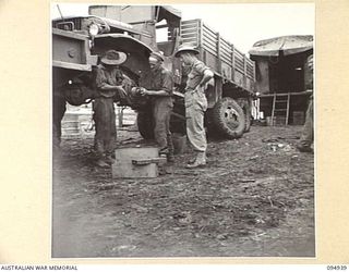 CAPE WOM, WEWAK AREA, NEW GUINEA. 1945-08-07. A 2-1/2 TON GENERAL MOTOR CORPORATION VEHICLE HOISTED UP BY A DIAMOND-T WRECKER, AT THE AUSTRALIAN ARMY SERVICE CORPS WORKSHOP, HEADQUARTERS COMMAND, ..