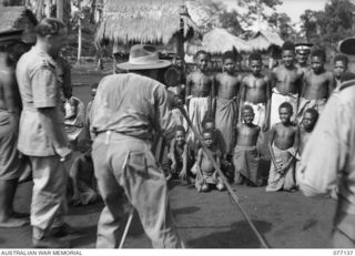 LAE, NEW GUINEA. 1944-11-27. NX95472 LIEUTENANT F.S. WOOD, PHOTOGRAPHER, MILITARY HISTORY SECTION, TAKING A MOVIE OF A CROWD OF CURIOUS NATIVES DURING HIS VISIT TO BUTIBUM VILLAGE. THIS VILLAGE HAS ..