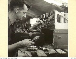 KILIGIA, NEW GUINEA. 1944-04-08. Q129147 SIGNALMAN G.H. HUGHES, "M" SECTION, 5TH DIVISION SIGNALS, AT HEADQUARTERS 5TH DIVISION TESTING VALVES FROM A NO. 11 SET WITH A MULTI-VALVE TESTER