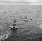 Willard Bascom on raft works on an oceanographic instrument, with John D. Isaacs and unidentified man in skiff, near Bikini Atoll