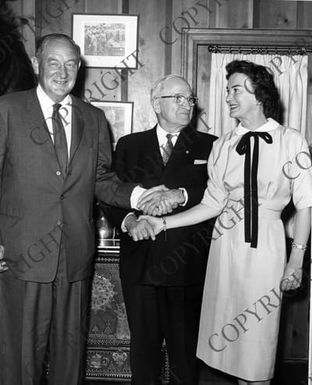 Edwin Pauley standing beside former President Truman shaking his left hand as Mrs. Pauley shakes his right hand