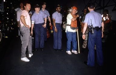 Sailors on the hangar deck of the amphibious assault ship USS SAIPAN (LHA-2) escort some of the American civilians who were evacuated from the U.S. Embassy in Monrovia, Liberia, to avoid the fighting between Liberian government forces and rebel factions