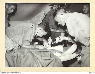 KALAI PLANTATION, HENRY REID BAY, NEW BRITAIN. 1945-03-05. PRIVATE W.N. WOOD, 19TH INFANTRY BATTALION BEING GIVEN A BLOOD TRANSFUSION BEFORE UNDERGOING A MAJOR OPERATION AT THE 6TH FIELD AMBULANCE