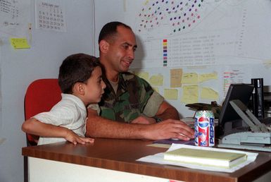 GUNNERY SGT. Luis Diaz, Facilities Maintenance, Combat Service Support Detachment 37, entertains an evacuee child with a lab-top computer