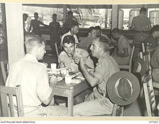 LAE AREA, NEW GUINEA. 1944-11-26. QX26074 GUNNER G.A. MCCLELLAND (1), QX30328 GUNNER G.R. OLLIER (2) QX27126 GUNNER G.R. WALTON (3) AND QX49399 GUNNER L.T. MCQUILLAND (4), ENJOYING A HOT MEAL AT ..