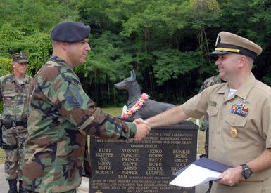 060801-N-9662L-030 (Aug. 1, 2006)US Air Force (USAF) MASTER SGT. Paul Capinas (left), assigned to the 36th Security Forces Squadron (SFS) at Andersen Air Force Base (AFB) Guam, shakes hands with US Navy (USN) CHIEF Warrant Officer William Norton, Security Officer Naval Security Force Guam, after his Reenlistment Ceremony held at the War Dog Memorial on board Naval Base Guam. The memorial is dedicated to war dogs, trained to serve as mine detectors, messengers and sentries during World War II (WW II). Twenty-five of the dogs were killed during fierce fighting on Guam in 1944, and were credited with saving hundreds of American lives. U.S. Navy photo by Mass Communication SPECIALIST Second...