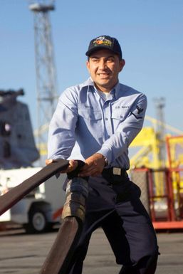 Aviation Boatswains Mate 3rd Class (AB3) Santos hauls a fuel hose across the flight deck of the amphibious assault ship USS SAIPAN (LHA 2)