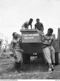 CAPE MOEM, NEW GUINEA. 1945-10-23. AUSTRALIAN NEW GUINEA ADMINISTRATIVE UNIT NATIVES, WORKING WITH 7 WAR GRAVES UNIT, UNLOADING CASKETS FROM A TRUCK FOR REBURIAL IN THE WEWAK WAR CEMETERY. THE ..