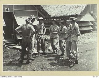 LAE, NEW GUINEA, 1945-05-07. SAPPERS ENGAGED IN BUILDING THE AUSTRALIAN WOMEN'S ARMY SERVICE BARRACKS IN BUTIBUM ROAD TALKING TO SOME OF THE AUSTRALIAN WOMEN'S ARMY SERVICE AFTER THEY HAD SETTLED ..