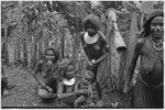 Women smoking, kundu drum hanging from fence