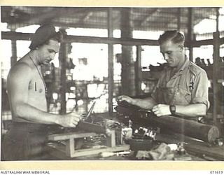 LAE, NEW GUINEA. 1944-03-24. Q114158 CRAFTSMAN A. L. MOROSOFF (LEFT) WITH TX4714 CRAFTSMAN W. C. BOUGHTWOOD (RIGHT), ARMOURERS PICTURED WORKING ON A RIFLE AND VICKERS MACHINE GUN IN THE ARMOURY ..