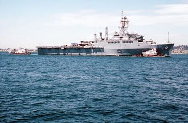 Crew members man the rails aboard the miscellaneous flagship USS CORONADO (AGF-11) as commercial harbor tugs maneuver the vessel toward port at Naval Air Station, North Island, San Diego. The CORONADO, flagship for Commander, Third Fleet, will be arriving at its new home port after being stationed in Hawaii for almost 20 years