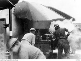 New Guinea. 1944-05. Members of the crew of HMAS Shropshire load a 4-inch gun during the shelling of enemy positions