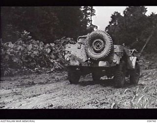 BULLDOG ROAD, NEW GUINEA. 1943-07-09. JEEP OF THE COMMAND ROYAL ENGINEERS NEGOTIATING A MUDDY PATCH OF ROAD AT THE 4 MILE POINT