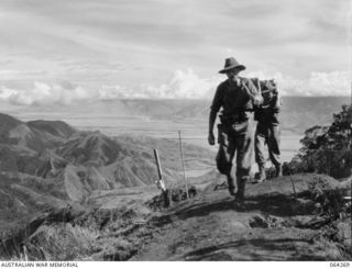 SHAGGY RIDGE, NEW GUINEA. 1944-01-22. LOOKING TOWARDS THE RAMU VALLEY FROM SHAGGY RIDGE SHOWING A MEMBER OF THE 2/9TH INFANTRY BATTALION BRINGING UP A SUPPLY OF AMMUNITION