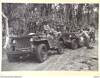 SOUTH BOUGAINVILLE. 1945-07-24. TROOPS OF V FIELD SECURITY SECTION, ATTACHED 3 DIVISION, ASSISTING TO PULL A BOGGED JEEP AND TRAILER OUT OF ONE OF THE MANY MUD HOLES ON THE BUIN ROAD, BETWEEN THE ..