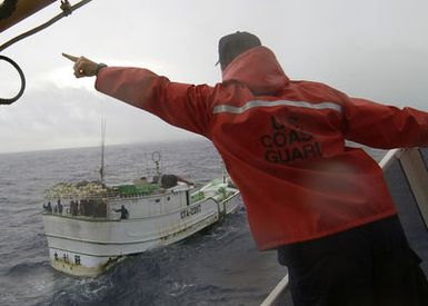 Onboard the US Coast Guard (USCG) Island Class; Patrol Craft, GALVESTON ISLAND (WPB 1349), Commanding Officer, Lieutenant (LT) Jerome E. Dubay signals to a civilian fishing boat known as a "long liner" to heave to and clear the harbor entrance, as the ship conducts escort operation into Apra Harbor, Guam