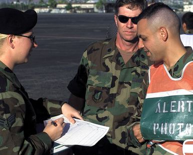 US Air Force Lieutenant Colonel Harvey Jones (Center), Security Alert Response Team (SART) Commander, observes Disaster Control Group (DCG), Alert PHOTO Representative Adrian Cadiz (Right), checking in at the security check point prior to entering the exercise search area on Hickam Air Force Base, Hawaii, on October 30th, 2000. This mission is in direct support of a MAJOR ACCIDENT RESPONSE EXERCISE (MARE)