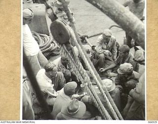 LAE, NEW GUINEA. 1944-06-14/02. AUSTRALIAN AND AMERICAN DOCKWORKERS ENJOYING A REST PERIOD ABOARD A SHIP OF THE 12TH WATER TRANSPORT OPERATING COMPANY