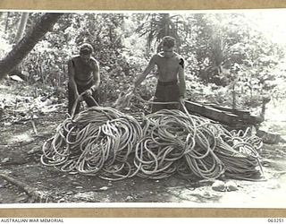 HUON GULF, NEW GUINEA. 1944-01-01. WX4794 CORPORAL A. W. JAMES (1) AND WX11709 PRIVATE E. T. CARROLL (2) OF THE 9TH DIVISION SALVAGE UNIT CHECKING A PILE OF ROPE ABANDONED BY THE RETREATING ..