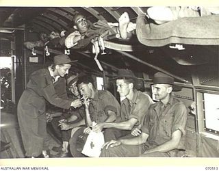 PORT MORESBY, PAPUA, 1944-02. LIEUTENANT "WOODIE" A. RAY, OF JEFFERSON, GEORGIA, AN AMERICAN NURSE LIGHTING A CIGARETTE FOR ONE OF THE AUSTRALIAN CASUALTIES WHO IS BEING FLOWN BACK FROM A FORWARD ..