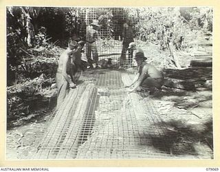 BOUGAINVILLE ISLAND. 1945-02-12. PERSONNEL OF THE 5TH COMPANY, LAYING AND FIXING WIRE MESH ON A TEMPORARY JEEP BRIDGE ON THE MOSIGETTA ROAD