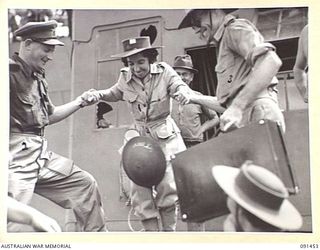 LAE, NEW GUINEA, 1945-05-07. PRIVATE R. MCNEAL, BEING HELPED ABOARD A LANDING BARGE DURING DISEMBARKATION FROM THE MV DUNTROON. SHE IS ONE OF 342 AUSTRALIAN WOMEN'S ARMY SERVICE EN ROUTE TO THE ..