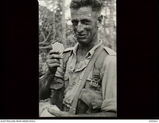 Donadabu, New Guinea. 1943-07-26. Q28352 Private C. H. Embrey of the 61st Battalion having a meal of bully beef and biscuits during a break in a supply dropping exercise