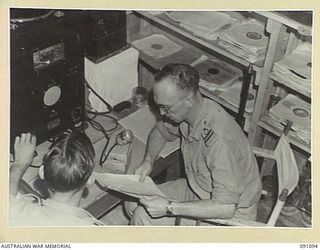 TOROKINA, BOUGAINVILLE. 1945-04-19. CORPORAL D.N. DWYER (1), WITH RED CROSS SOCIETY REPRESENTATIVE E.H. PRICE (2), AT 2/3 CONVALESCENT DEPOT PUBLIC ADDRESS SYSTEM ARRANGING THE PROGRAMME FOR TROOPS ..