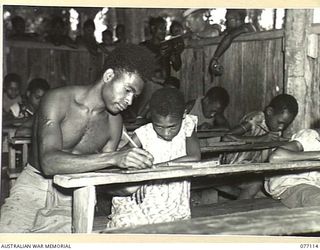 LAE, NEW GUINEA. 1944-11-27. IOSI, THE NATIVE SCHOOL TEACHER AT BUTIBUM VILLAGE EXPLAINING A PROBLEM TO A VERY SHY NATIVE GIRL IN THE CLASS. THIS VILLAGE HAS BEEN TAKEN OVER BY THE AUSTRALIAN NEW ..