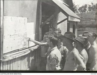 PORT MORESBY, PAPUA. C. 1944-05. MEMBERS OF THE RAAF AIRCRAFT REPAIR DEPOT READING A WALL NEWSPAPER