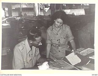 LAE, NEW GUINEA. 1945-05-15. CORPORAL R.J. HOTSON (1), INSTRUCTING CORPORAL E.M. CHARTERS (2), AT A BRANCH, HEADQUARTERS FIRST ARMY. A FEW DAYS AFTER THEIR ARRIVAL FROM AUSTRALIA AUSTRALIAN WOMEN'S ..