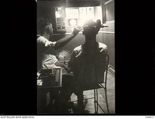 Port Moresby, New Guinea. 1944-05-13. Private R. E. Welladsen, a member of the Ophthalmic Section, 128th Australian General Hospital, testing the eyesight of a patient with the Snellen's Test chart