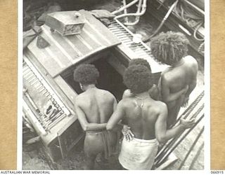 PORT MORESBY, NEW GUINEA. 1944-06-14/02. NEW GUINEA BOYS INTERESTEDLY WATCHING THE ENGINES ON ONE OF THE SHIPS OF THE 12TH SMALL SHIPS COMPANY