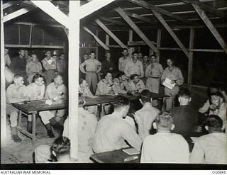 KIRIWINA, TROBIAND ISLANDS, PAPUA. C. 1944-03. IN THE AIRMEN'S MESS OF NO. 30 (BEAUFIGHTER) SQUADRON RAAF: OFFICERS VERSUS AIRMEN IN A DEBATE ON THE TOPIC OF MERCY KILLING